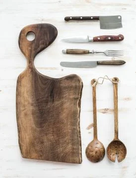 Kitchen-ware set. Old rustic chopping board made of walnut wood, knives, fork Stock Photos
