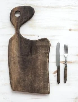 Kitchen-ware set. Old rustic chopping board made of walnut wood, knife, fork  Stock Photos