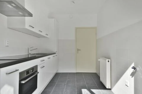 A kitchen with white cabinets and a black counter top Stock Photos