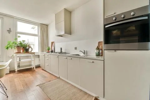 A kitchen with white cabinets and a large window Stock Photos