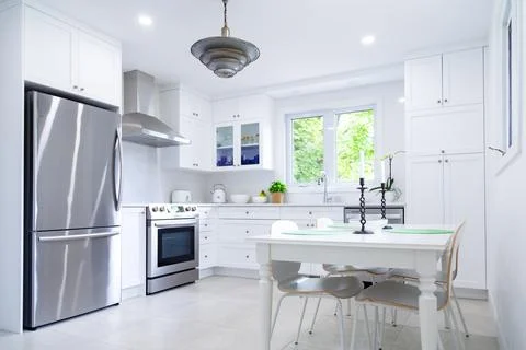 Kitchen with white cabinets, table and chairs Stock Photos