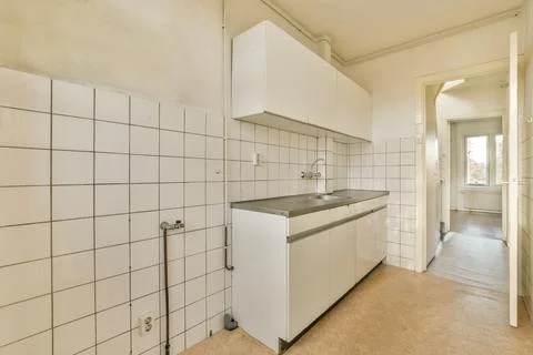 A kitchen with white tiled walls and a sink Stock Photos