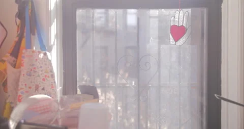 Kitchen window with heart stained glass ornament, aprons, dishes, iron grate Stock Footage 169736264