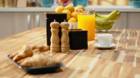 Kitchen with wooden breakfast table with pastry and fruits in empty home Stock Footage 330440897