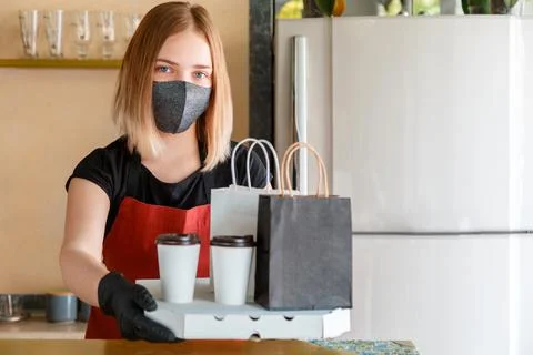 Kitchen worker portrait issues online orders in gloves and mask. Takeaway foo Stock Photos