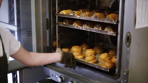Kitchen worker takes out the buns from the oven Stock Footage 69742126