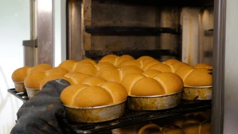 Kitchen worker takes out the buns from the oven in bakery. Stock Footage 108099945