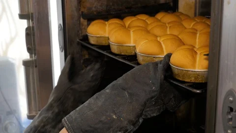 Kitchen worker takes out the buns from the oven in bakery. Stock Footage 108635195