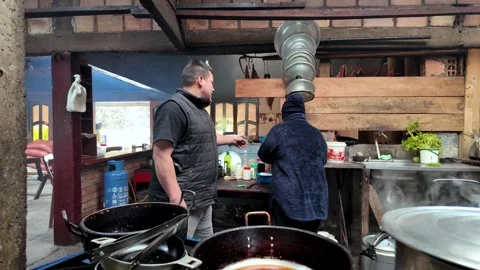 Kitchen workers preparing hot breakfast in a cozy rustic roadside restaurant Stock Footage 335919683