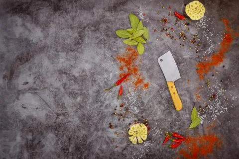 Kitchenware cleaver and spices on dark background. Stock Photos