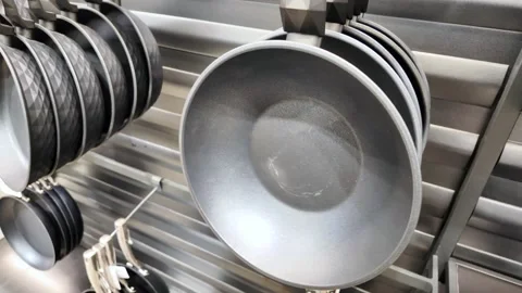 Kitchenware display featuring modern nonstick frying pans hanging on metal .. Stock Footage 332202516