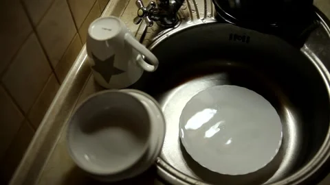 Kitchenware, plates and cups in the sink, water dripping into the plate. Stock Footage 169820058