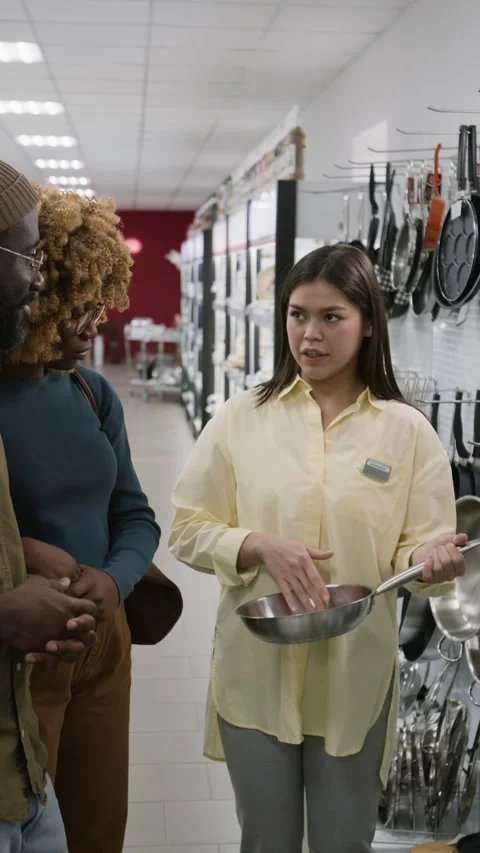 Kitchenware Store Assistant Advertising Frying Pan to Young Black Couple Stock Footage 321770915