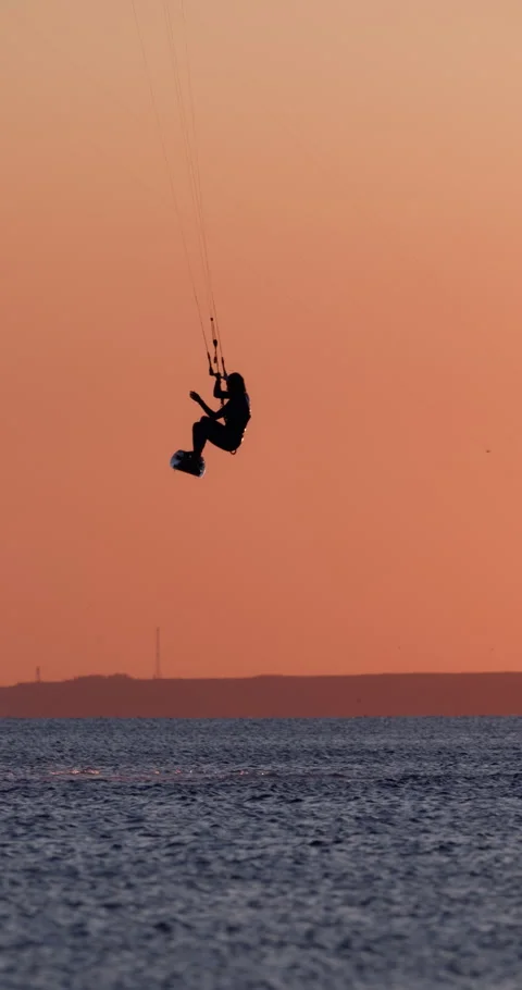 Kite boarder riding and jumping on sea water with warm sunset light Stock Footage 345366872