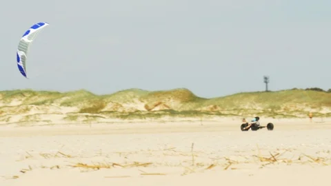 Kite buggying - A pilot in a buggy rolls through the deserted sandy beach Stock Footage 90397898