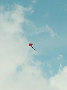 A kite is flying in the sky above a cloudy blue sky Stock-Fotos