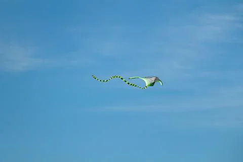 Kite flying under bright sun and clouds Stock Photos