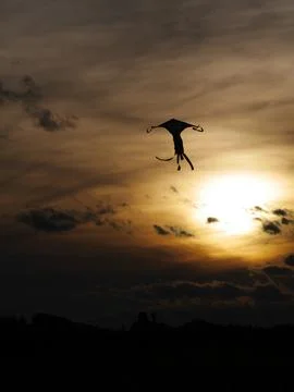 Kite flying under a dramatic sky at sunset Stock Photos