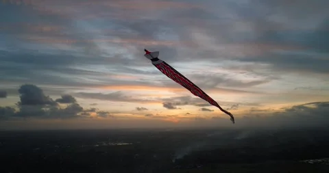Kite soaring in the evening sky, among clouds at sunset Stockbeeldmateriaal 274626132