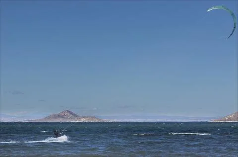 Kite surfer holding onto the sail while being towed along Stock Photos