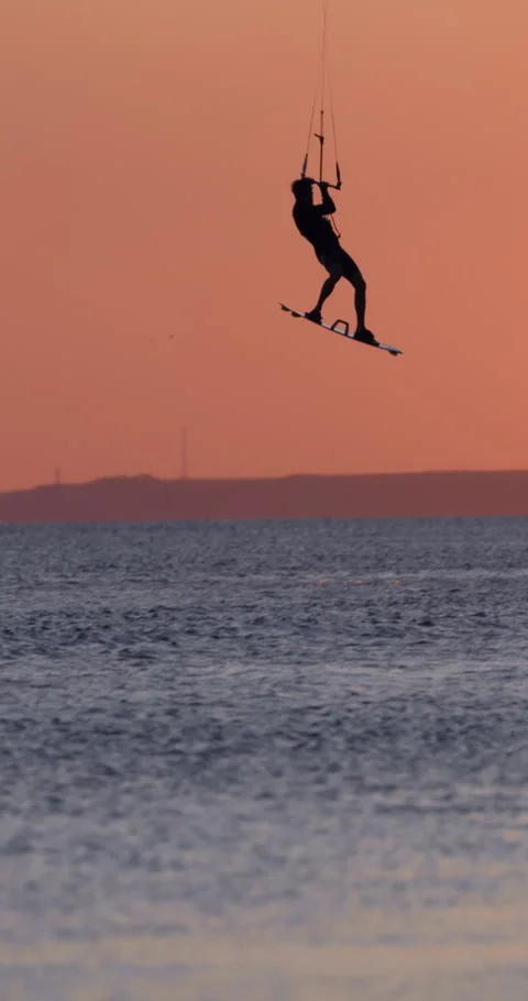 Kite surfer riding and jumping on sea water with warm sunset light Stock Footage 345127973