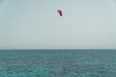 Kite surfer riding ocean waves on a bright sunny day Stock Photos