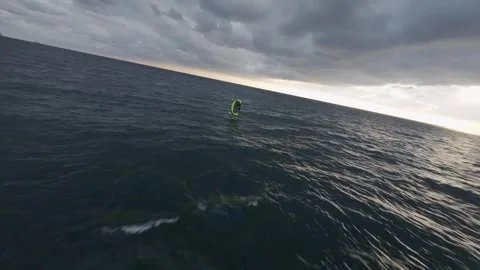Kite surfer riding waves at dusk near Genoa, Italy, with cloudy skies, FPV Stock Footage 263863742