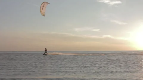 Kite surfer surfing at ocean at sunset wide shot pan 3 Stock Footage 44392813