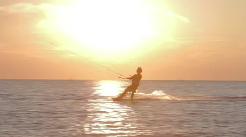 Kite surfer surfing at ocean at sunset medium wide shot pan Stock Footage 44395079