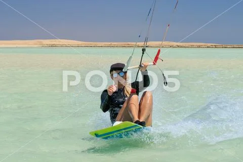 Kite surfing girl in sexy swimsuit with kite in sky on board in blue sea Stock Photos