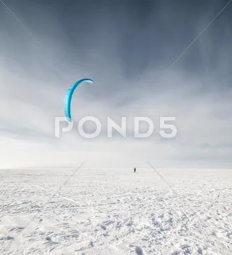 Kiteboarder with blue kite on the snow Stock Photos