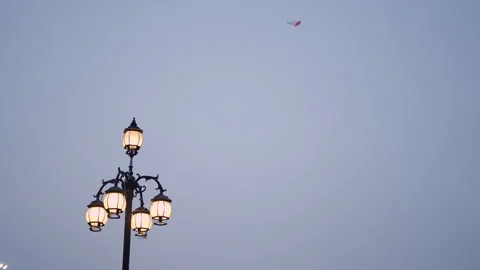 Kites flying by the force of the wind on a cloudy day near a lit street lamp at Stock Footage 278694570