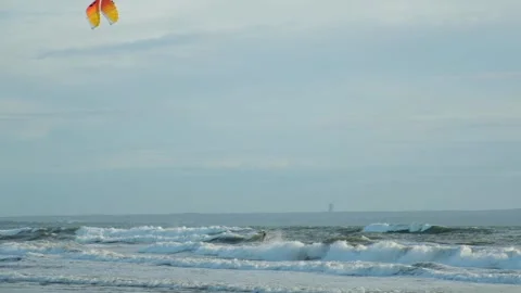 A kitesurfer is preparing for the competition. He rides a board on the waves Stock Footage 214671109