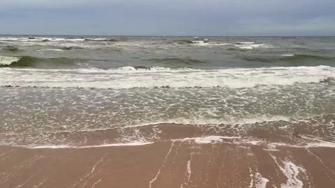Kitesurfers riding waves in the ocean on a cloudy day Stock Footage 320723934