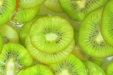 Kiwi fruit close-up in liquid with bubbles. Slices of green ripe kiwi fruit in Fotos de archivo