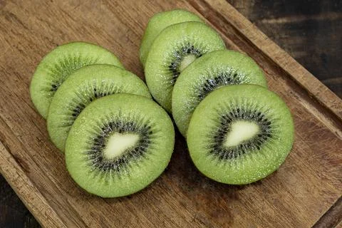 Kiwi fruit slice in cutting board isolated on wood background Stock Photos