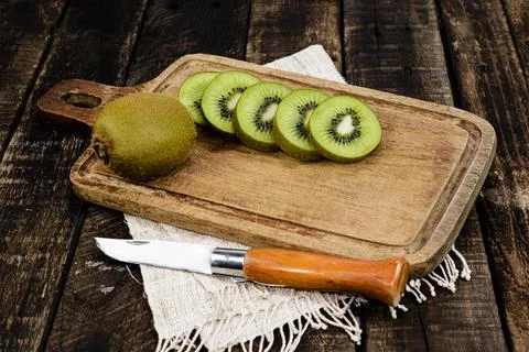 Kiwi fruit slice in cutting board have knife isolated on wood background Stock Photos