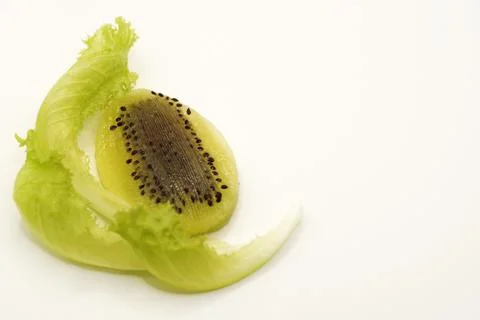 Kiwi in the shape of an Easter egg cut in half next to a lettuce leaf Stock Photos