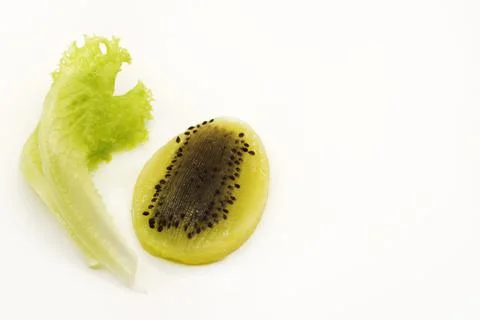 Kiwi in the shape of an Easter egg cut in half next to a lettuce leaf Stock Photos