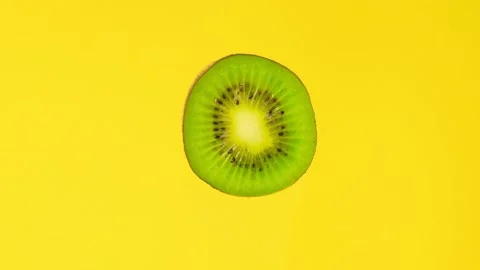 Kiwi slice rotating front view on yellow background. Macro food. Looped rotation Stock Footage 198048480