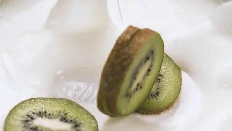 Kiwi slices falling into yogurt with splashes, slow motion. Stock Footage 84953585