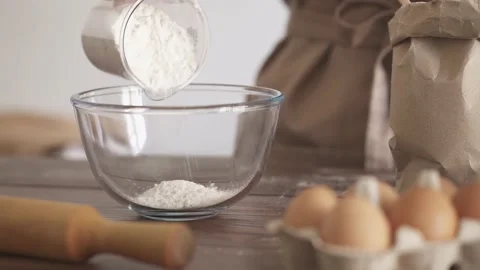 Kneading the dough. The chef pours the flour from a measuring glass into a t Stock Footage