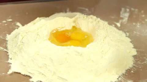 Kneading dough close view. Adding eggs in flour. Video stock 146946418
