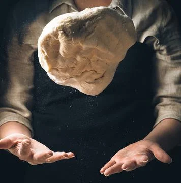 Kneading the dough, the cook throws the dough. Levitation of food. Stock Photos