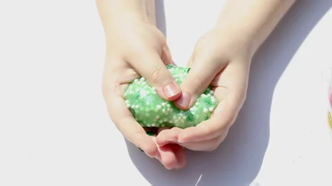 Kneading process, playing with slime, children's hands put the slime in a Stock Footage 157326007