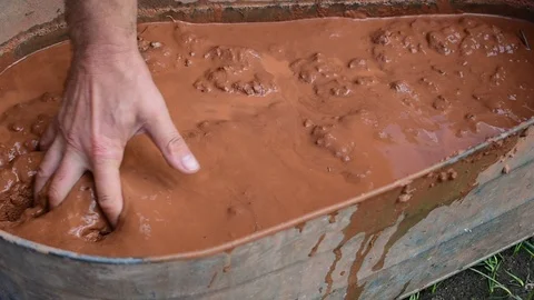 Kneads clay in a large bath Stock Footage 117472604