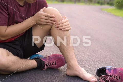 Knee Injuries. Young sport man holding knee with his hands in pain after suff Stock Photos
