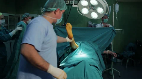 Knee surgery. Surgeon preparing patient for knee operation on operating table. Stock Footage 34914448