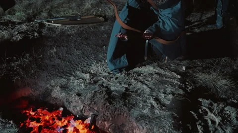 Kneeling bound medieval soldier in chainmail and cloak under ember glow, cold Stock Footage 343684556