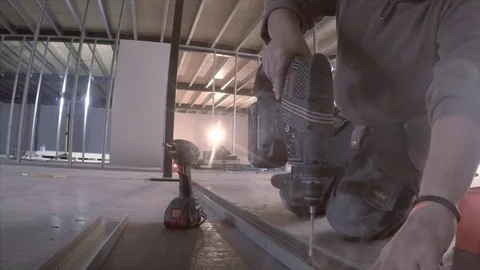 Kneeling builder drills holes on construction site 스톡 동영상 78771003